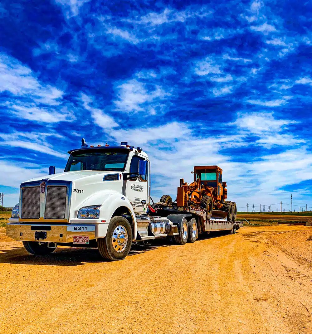 Construction equipment hauling on flatbed truck in Washington County Utah — excavators and heavy machinery transport